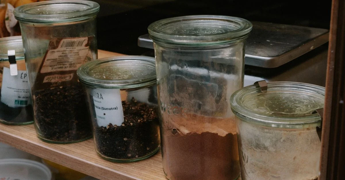 Une variété d'épices conservées dans des bocaux en verre alignés sur une étagère, parfaits pour l'organisation de la cuisine.