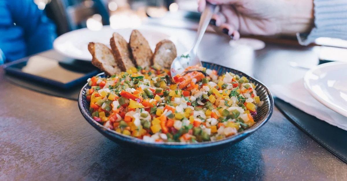 Un plat de légumes vibrant avec du pain tranché sur une table, parfait pour un repas sain.
